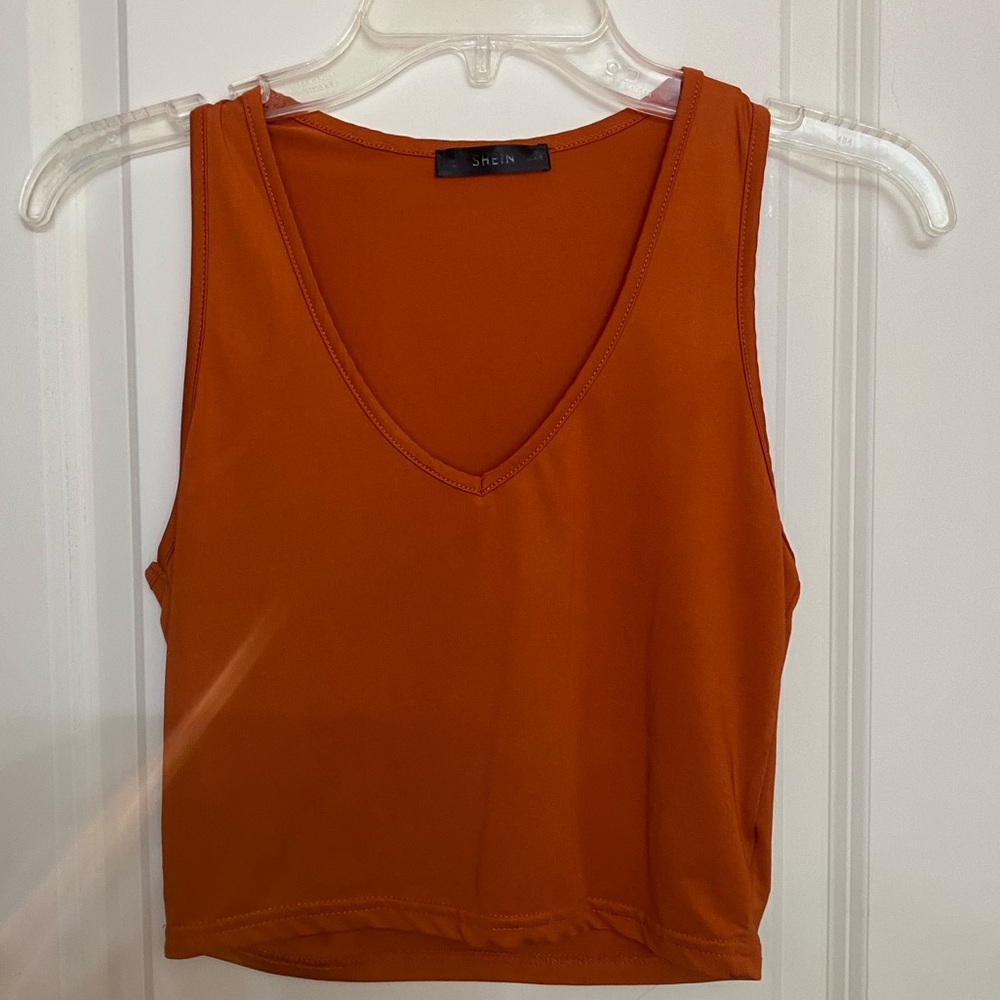Orange V-neck crop top with a scooped neckline and raw hem